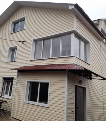 Ванильный сайдинг GRAND LINE на фасаде большого дома.