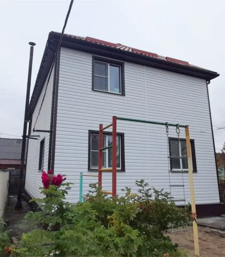 Белый сайдинг GRAND LINE для дома с красной крышей.